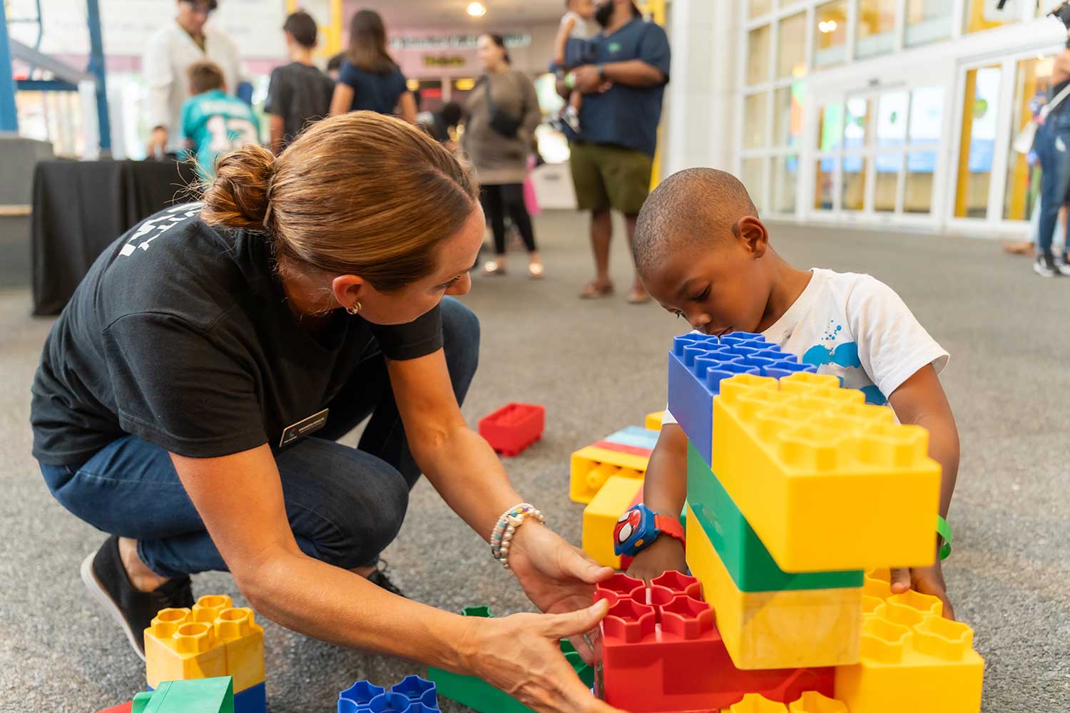 The Center staff assist a young child with building activity at creative program in South Florida.